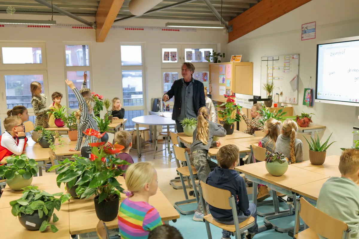 Klaslokaal vol planten met kinderen en een leerkracht