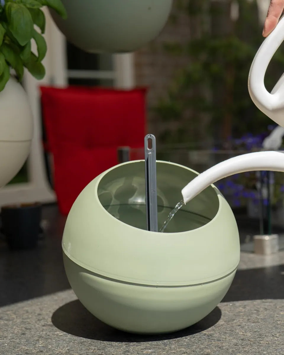 Water geven in een groene Globee op een tuintafel