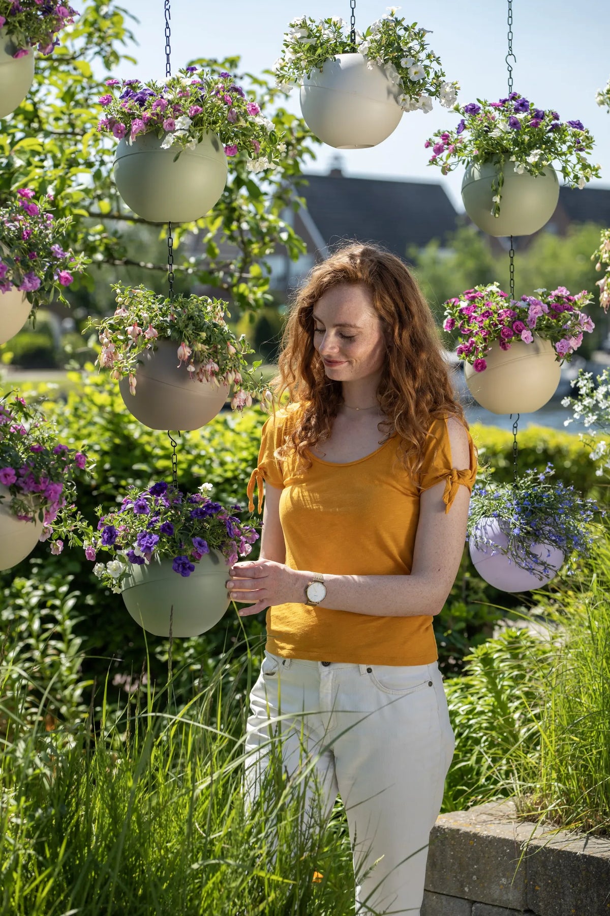 Vrouw in haar tuin tussen hangende Globees met bloemen aan kettingen